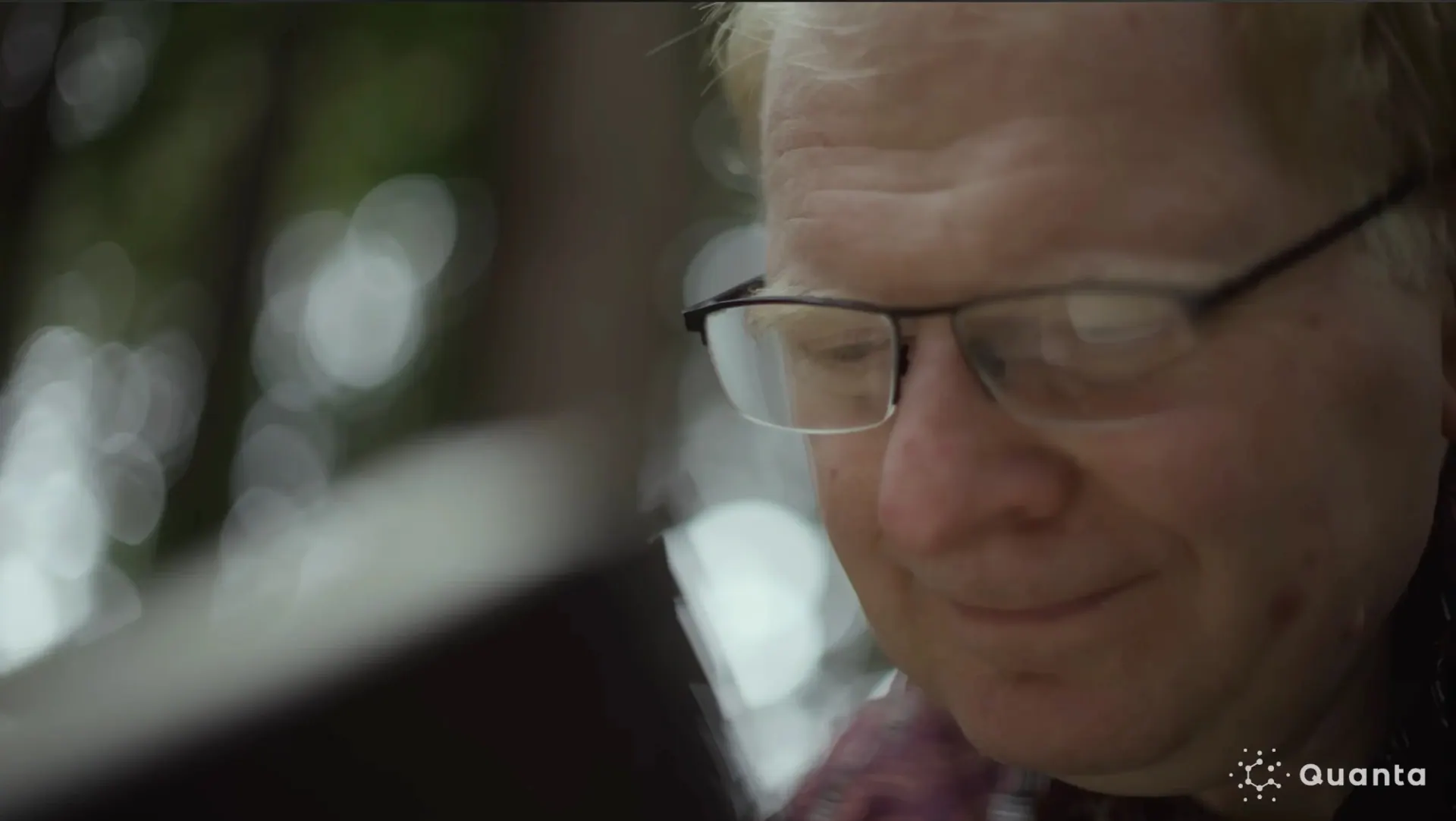 Close-up of a scientist smiling as he looks down, from Quanta Magazine's computer vision film